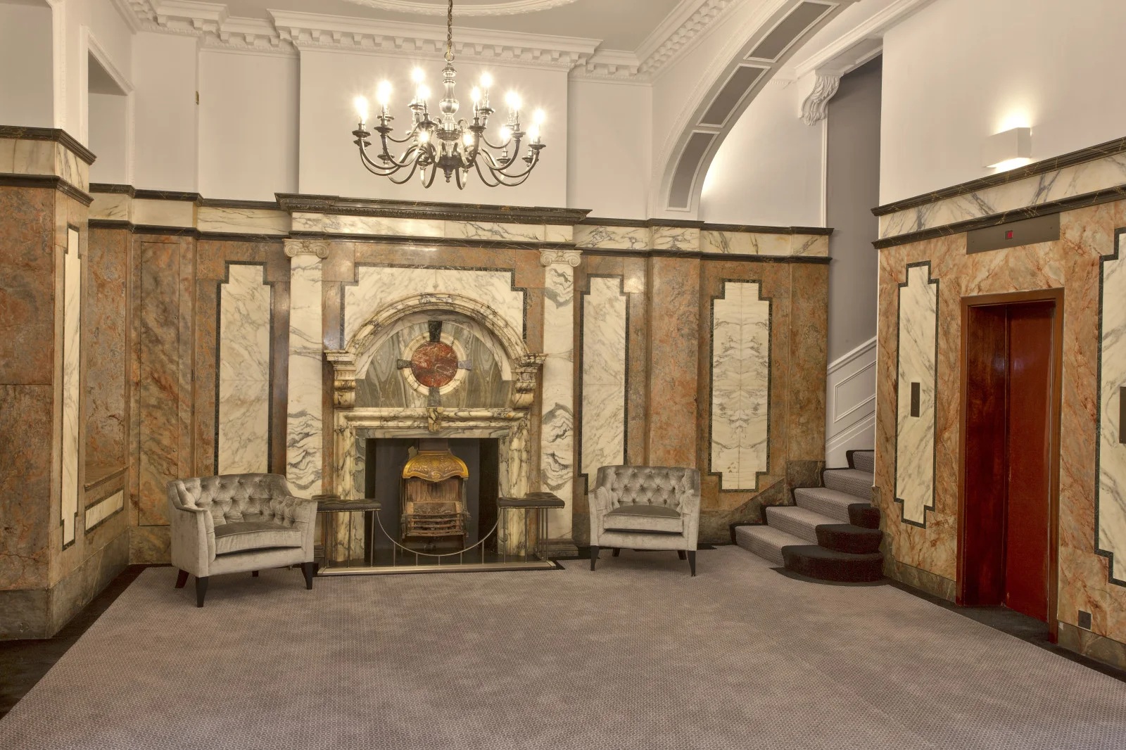 Marble entrance hall with a chandelier and fireplace