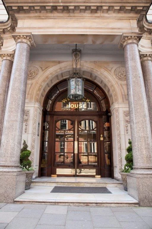 Arched entrance doors and stone columns of a Welbeck Street mansion block