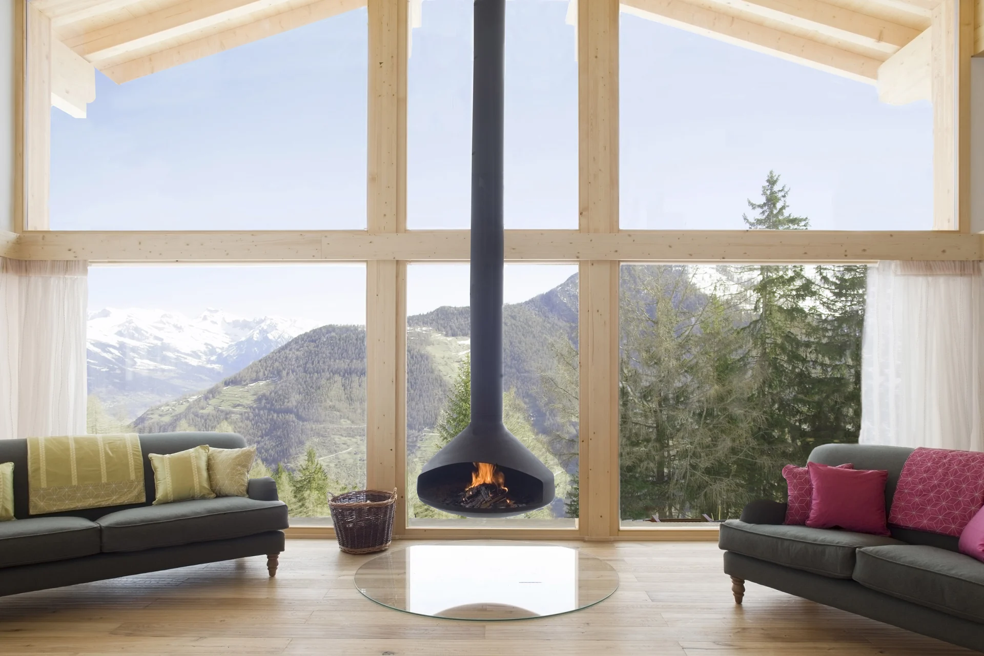 Chalet living room with a suspended fireplace and floor-to-ceiling mountain views